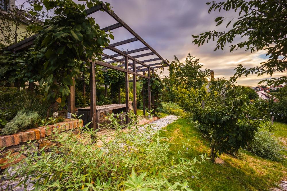 Pergola s posezením a kamennou cestou v parčíku Do Kaštan za podvečerního světla
