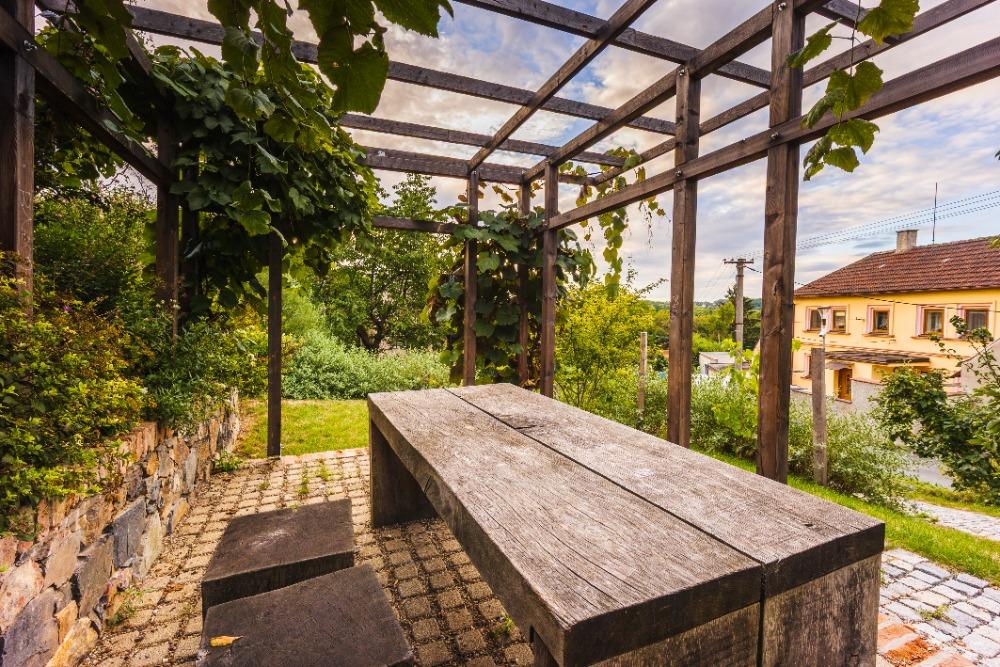 Kamenný stůl s lavicemi pod pergolou v parčíku Do Kaštan