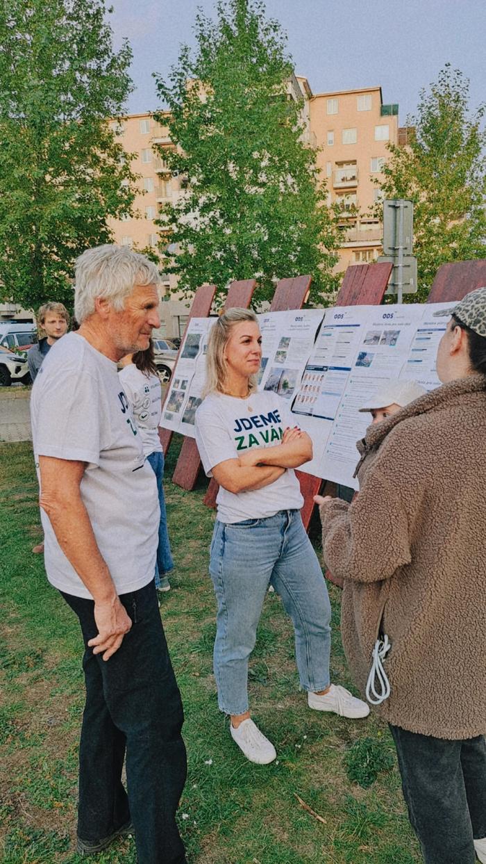 Kandidáti v tričkách s nápisem Jdeme za vámi hovoří s návštěvnicí u informačních panelů