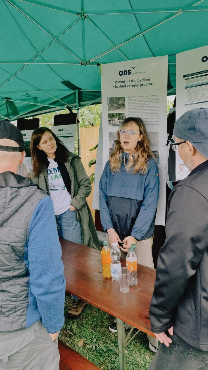 Žena odpovídá návštěvníkům u informačního panelu