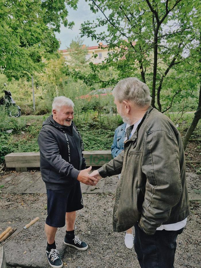 Dva muži si podávají ruku na cestě u hřiště