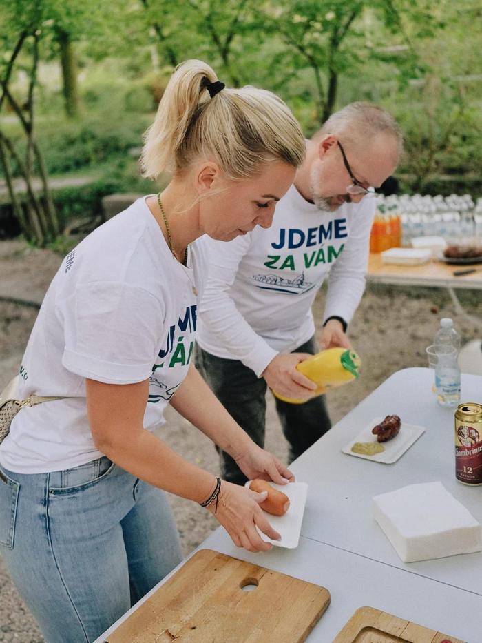 Dva lidé chystají na stole občerstvení