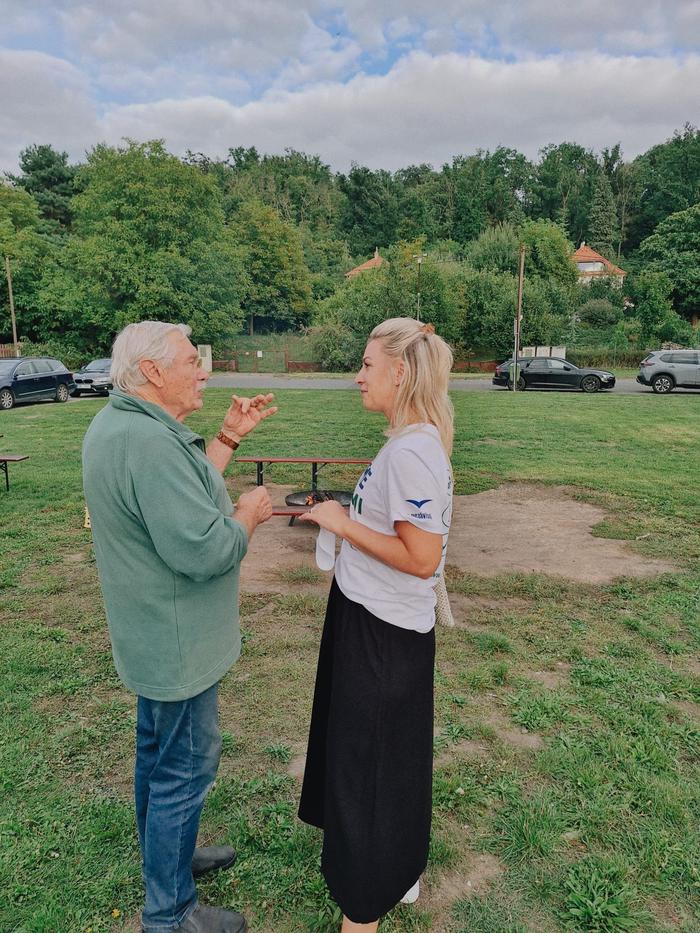 Muž a žena spolu hovoří na louce u řeky